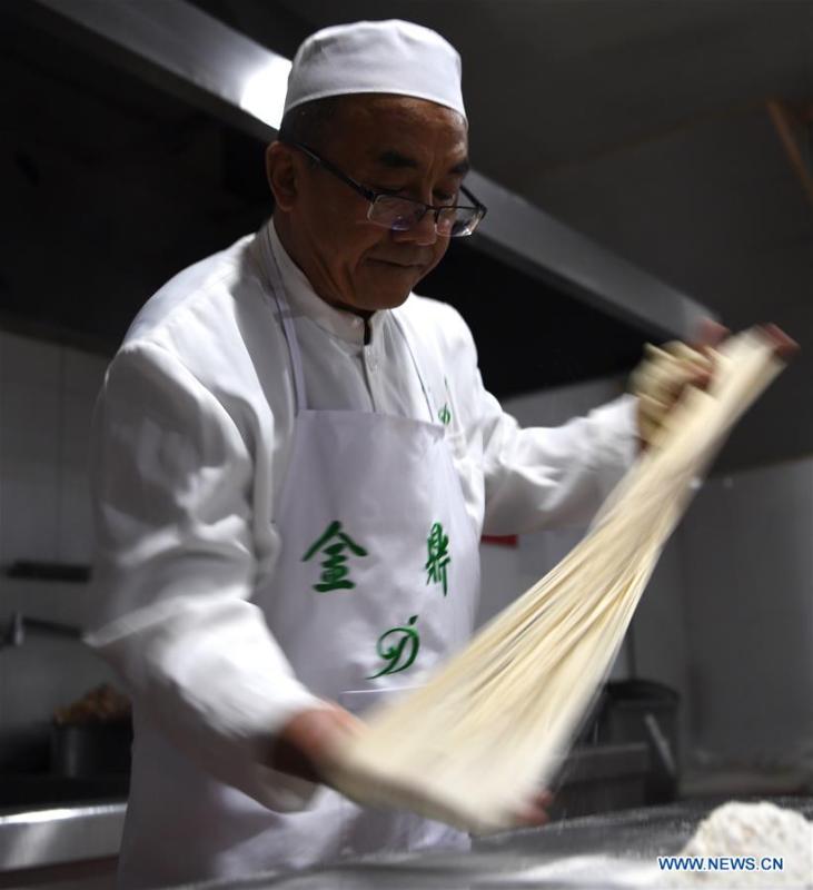 Ma Wenbin, an inheritor of Lanzhou beef noodle, pulls noodles at a beef noodle restaurant in Lanzhou, capital of northwest China\'s Gansu Province, April 2, 2019. Lanzhou beef noodles, a Chinese hand-pulled noodle originated in Lanzhou, has a history of about 100 years. There are about ten types of noodles of different width and shapes, depending on noodle chefs\' pulling skills. It has won fame both at home and abroad with its speciality of noodles and soup recipe. (Xinhua/Fan Peishen)