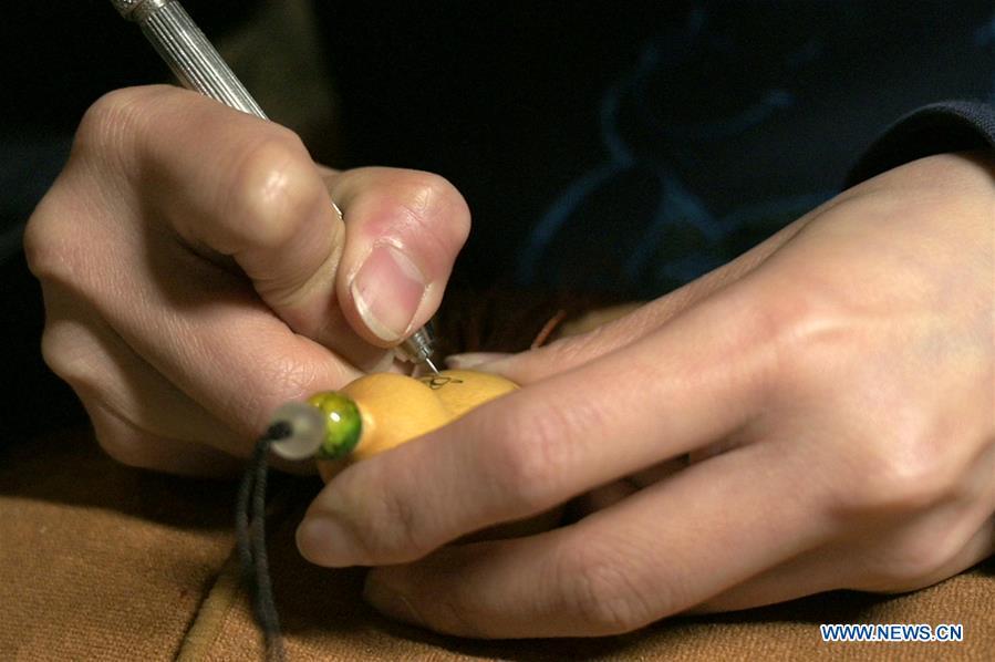 Photo taken on March 31, 2019 shows Ruan Yizhou, an arts and crafts master of Gansu Province, making a carved gourd at a gourd carving studio in Lanzhou, northwest China\'s Gansu Province. A carved gourd, as the name suggests, is a gourd carved with landscapes, portraits, animals, calligraphy or poems, and then painted with ink. The process of gourd carving includes choosing gourd, painting, engraving and coloring. It was inscribed in the first group of provincial intangible cultural heritages of Gansu in 2006. (Xinhua/Liu Jie)