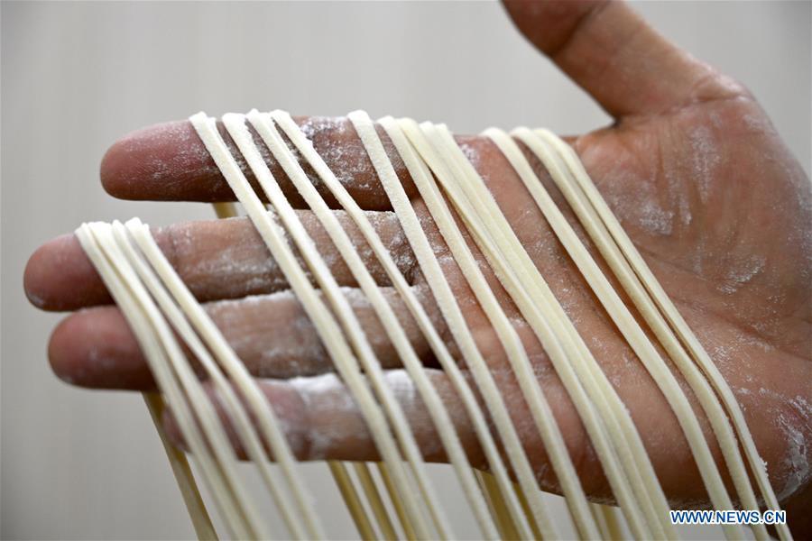 Ma Wenbin, an inheritor of Lanzhou beef noodle, pulls noodles at a beef noodle restaurant in Lanzhou, capital of northwest China\'s Gansu Province, April 2, 2019. Lanzhou beef noodles, a Chinese hand-pulled noodle originated in Lanzhou, has a history of about 100 years. There are about ten types of noodles of different width and shapes, depending on noodle chefs\' pulling skills. It has won fame both at home and abroad with its speciality of noodles and soup recipe. (Xinhua/Liu Jie)