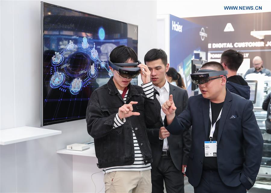 A visitor tries MR (Mixed reality) devices at the booth of China\'s consumer electronics and home appliances company Haier at Hanover Fair 2019 in Hanover, Germany, April 1, 2019. Over 1,400 Chinese exhibitors attended the fair, the second most just after the host country Germany. Huawei, Haier and other Chinese manufacturers showed their most advanced networking and artificial intelligence technologies to the world. (Xinhua/Shan Yuqi)