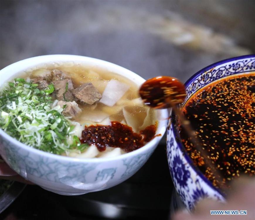A noodle chef adds chili oil to noodles at a beef noodle restaurant in Lanzhou, capital of northwest China\'s Gansu Province, April 2, 2019. Lanzhou beef noodles, a Chinese hand-pulled noodle originated in Lanzhou, has a history of about 100 years. There are about ten types of noodles of different width and shapes, depending on noodle chefs\' pulling skills. It has won fame both at home and abroad with its speciality of noodles and soup recipe. (Xinhua/Li Xiao)
