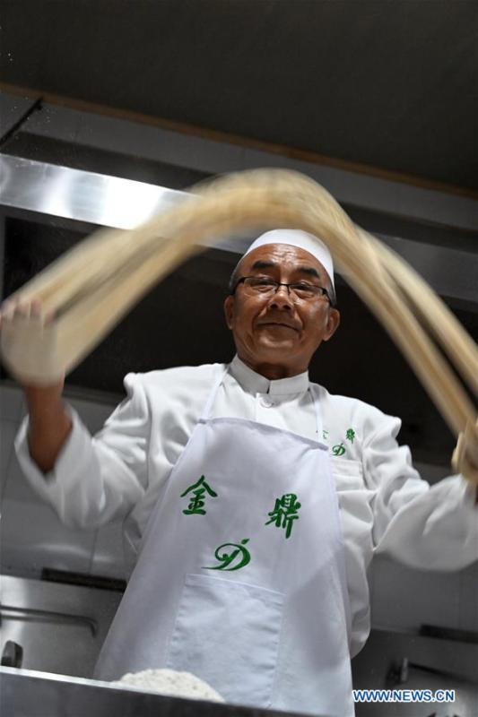 Ma Wenbin, an inheritor of Lanzhou beef noodles, pulls noodles at a beef noodle restaurant in Lanzhou, capital of northwest China\'s Gansu Province, April 2, 2019. Lanzhou beef noodles, a Chinese hand-pulled noodle originated in Lanzhou, has a history of about 100 years. There are about ten types of noodles of different width and shapes, depending on noodle chefs\' pulling skills. It has won fame both at home and abroad with its speciality of noodles and soup recipe. (Xinhua/Liu Jie)
