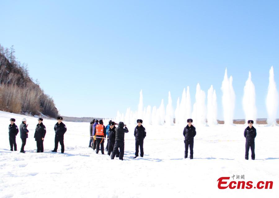 Police officers stand guard as ice is blasted to create safe passage for ships on the still-frozen Tahe section of Heilongjiang River in Northeast China\'s Heilongjiang Province, April 3, 2019. As the weather starts to warm after the extreme cold of winter, local authorities detonate the thick ice to allow vessels to start work again.  (Photo/China News Service)