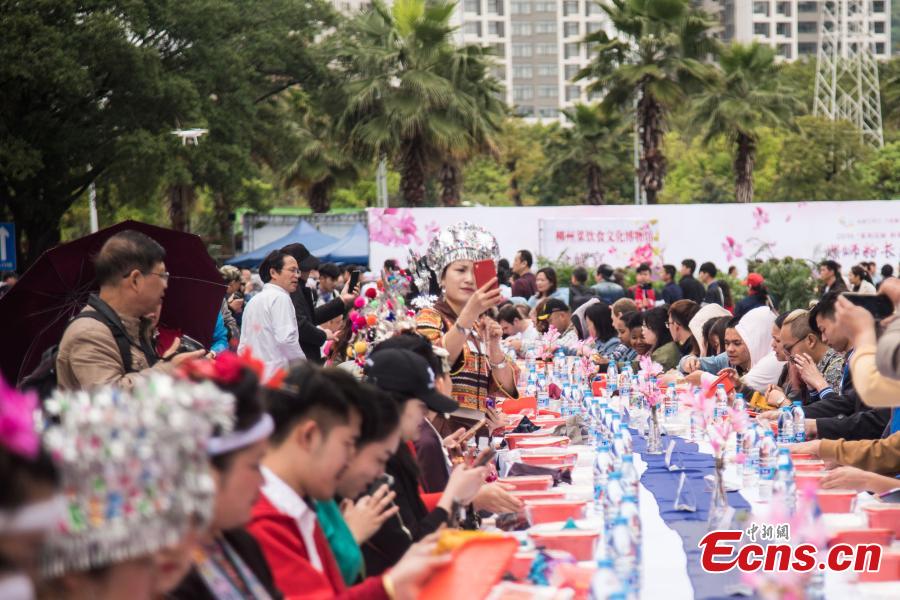 People eat Luosifen, a local rice noodle dish featuring cooked river snails as ingredient, at a long-table feast in Liuzhou, south China\'s Guangxi Zhuang Autonomous Region, April 3, 2019. More than 2,000 people joined the feast which was served on tables measuring 1,000 meters in length here on Wednesday.  (Photo/China News Service)