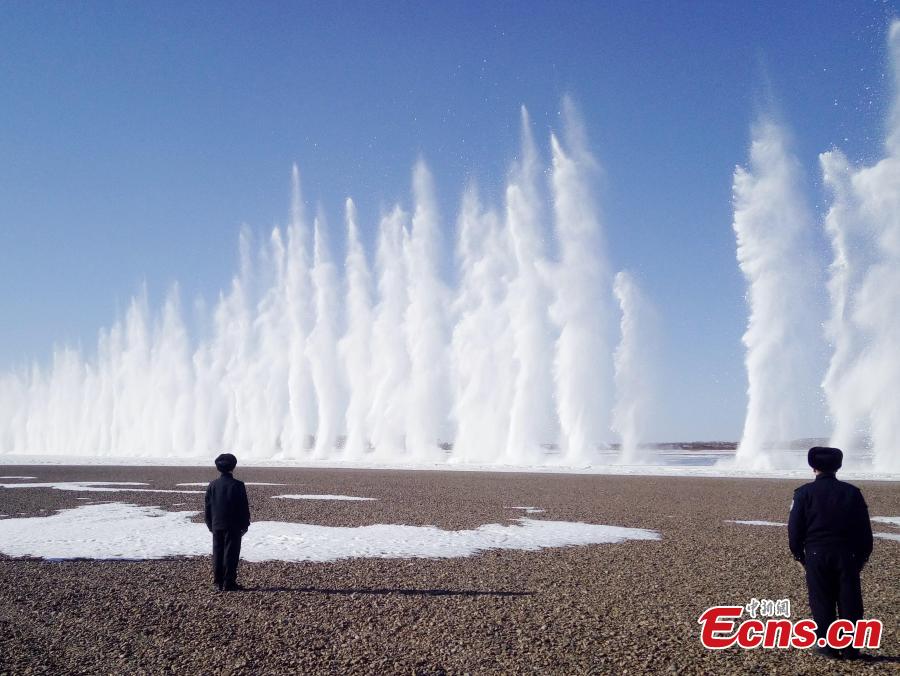 Police officers stand guard as ice is blasted to create safe passage for ships on the still-frozen Tahe section of Heilongjiang River in Northeast China\'s Heilongjiang Province, April 3, 2019. As the weather starts to warm after the extreme cold of winter, local authorities detonate the thick ice to allow vessels to start work again.  (Photo/China News Service)