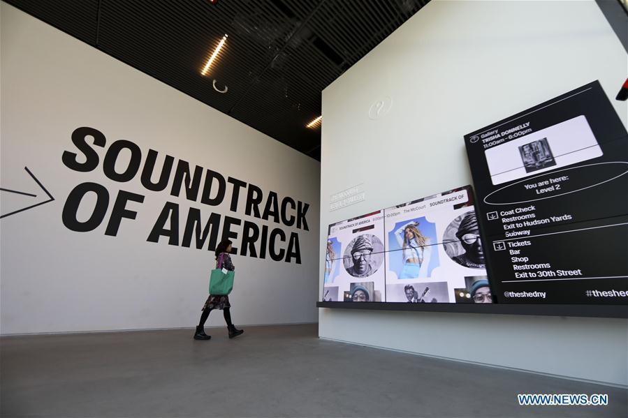 A visitor walks past screens during a media preview in The Shed, a new arts center in New York, the United States, on April 3, 2019. The Shed, New York City\'s new arts center that commissions, develops, and presents original works of art, across all disciplines, for all audiences, will open to the public on April 5 with the world premiere of Soundtrack of America. (Xinhua/Wang Ying)