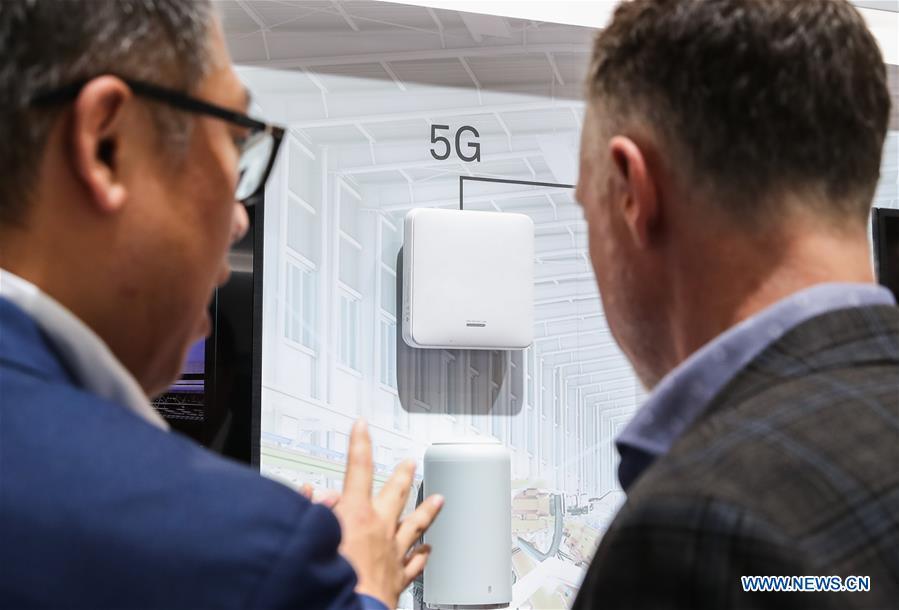 A staff member (L) introduces a Huawei product as a visitor looks on at the booth of Huawei during the 2019 Hanover Fair in Hanover, Germany, April 3, 2019. (Xinhua/Shan Yuqi)