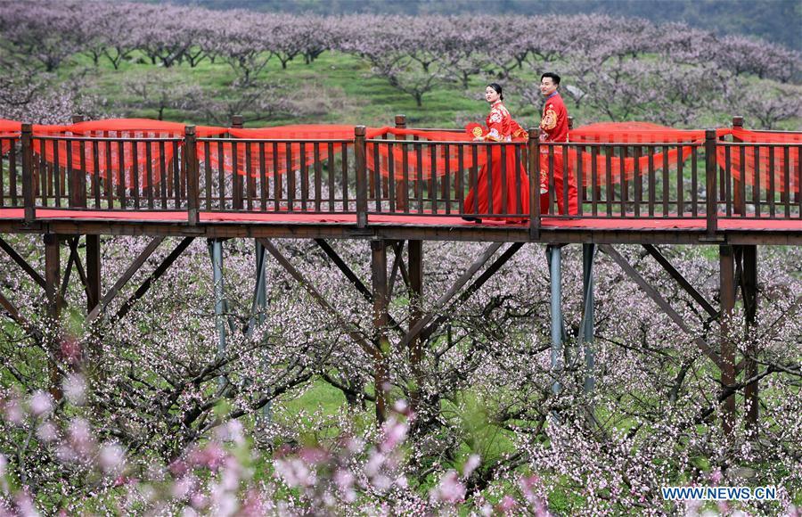 A newly-wed couple view flowers in Wude Town of Shiqian County, southwest China\'s Guizhou Province, April 4, 2019. A group wedding ceremony in traditional style was held here Thursday for couples who have been striving on the frontline for the county\'s fight against poverty. (Xinhua/Yang Wenbin)