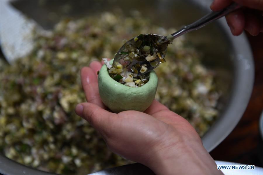 A villager makes Qingtuan, or green sticky rice balls, in Yiyanshan Village of Huzhou, east China\'s Zhejiang Province, April 4, 2019. Qingtuan, made from glutinous rice mixed with wormwood juice and stuffed with bamboo shoot, tofu and preserved meat, is a traditional snack popular mailnly among people living in the south of Yangtze River during the Qingming Festival also known as Tomb Sweeping Day. (Xinhua/Huang Zongzhi)