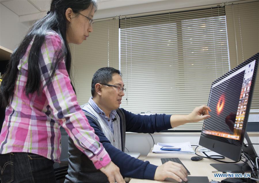 Chinese researchers Lu Rusen (R) and Huang Lei discuss the imaging methods of the image of a black hole in Shanghai Astronomical Observatory (SAO), in east China\'s Shanghai, April 9, 2019. The image of the black hole, based on observations through the Event Horizon Telescope (EHT), a planet-scale array of eight ground-based radio telescopes forged through international collaboration, was unveiled in coordinated press conferences across the globe at around 9:00 p.m. (Beijing time) on Wednesday. The landmark result offers scientists a new way to study the most extreme objects in the universe predicted by Albert Einstein\'s general relativity. (Xinhua/Jin Liwang)