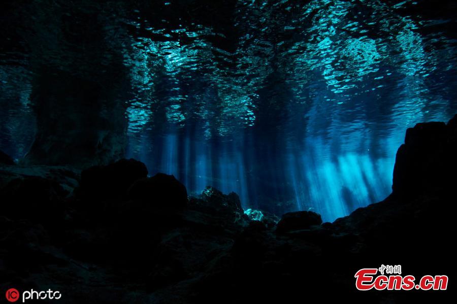 Photo taken by Kirk Zhang shows people diving in freshwater in cenotes illuminated with sunlight from the outside in Mexico. Diving in the caverns, windows to large underground river systems, is a unique experience with  amazing light effects. (Photo/IC)