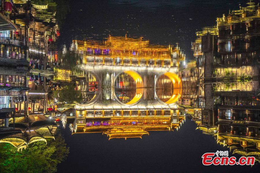 Illuminated buildings are reflected in the Tuojiang River in Fenghuang Ancient Town, Hunan Province, April 11, 2019. The old town is famous for its time-honored buildings and cultural relics, attracting large numbers of visitors each year from China and abroad. (Photo: China News Service/Yang Huafeng)