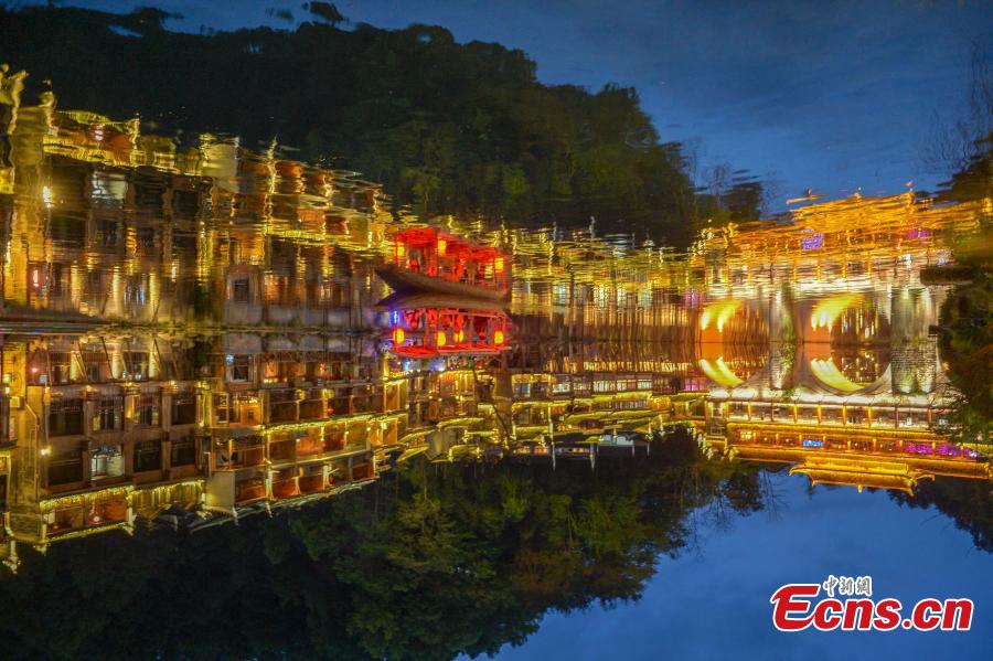 Illuminated buildings are reflected in the Tuojiang River in Fenghuang Ancient Town, Hunan Province, April 11, 2019. The old town is famous for its time-honored buildings and cultural relics, attracting large numbers of visitors each year from China and abroad. (Photo: China News Service/Yang Huafeng)