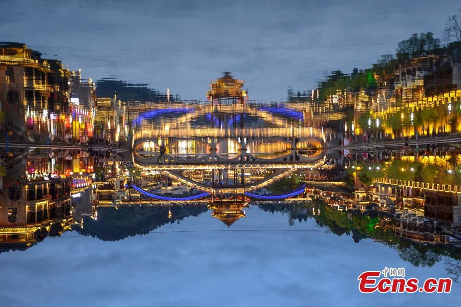 Illuminated buildings are reflected in the Tuojiang River in Fenghuang Ancient Town, Hunan Province, April 11, 2019. The old town is famous for its time-honored buildings and cultural relics, attracting large numbers of visitors each year from China and abroad. (Photo: China News Service/Yang Huafeng)