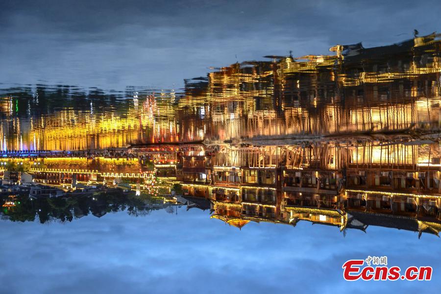 Illuminated buildings are reflected in the Tuojiang River in Fenghuang Ancient Town, Hunan Province, April 11, 2019. The old town is famous for its time-honored buildings and cultural relics, attracting large numbers of visitors each year from China and abroad. (Photo: China News Service/Yang Huafeng)