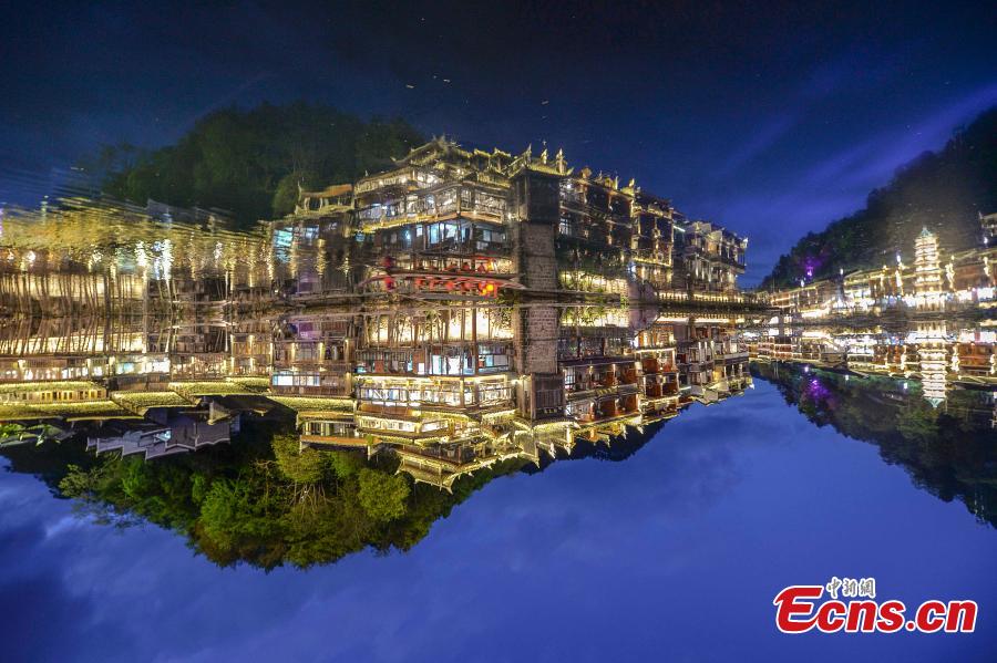 Illuminated buildings are reflected in the Tuojiang River in Fenghuang Ancient Town, Hunan Province, April 11, 2019. The old town is famous for its time-honored buildings and cultural relics, attracting large numbers of visitors each year from China and abroad. (Photo: China News Service/Yang Huafeng)