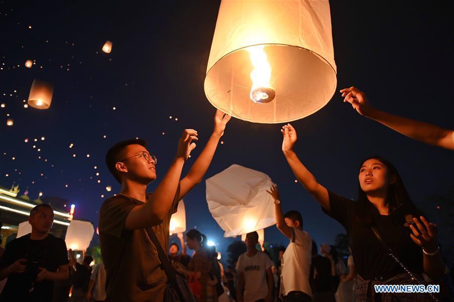 People fly Kongming lanterns, a kind of small hot-air paper balloon, by the Lancang River in Jinghong City, southwest China\'s Yunnan Province, April 13, 2019, to celebrate the New Year of the calendar of the Dai ethnic group. (Xinhua/Qin Qing)