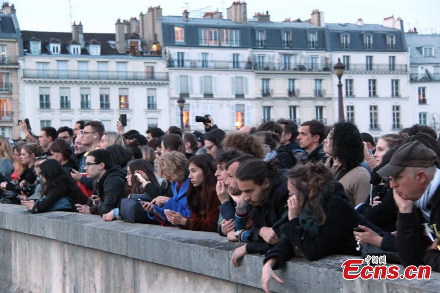 People look at the fire on the Notre Dame Cathedral in central Paris, capital of France, on April 15, 2019. A blaze broke out on Monday afternoon at the Notre Dame Cathedral in central Paris.  (Photo/China News Service)