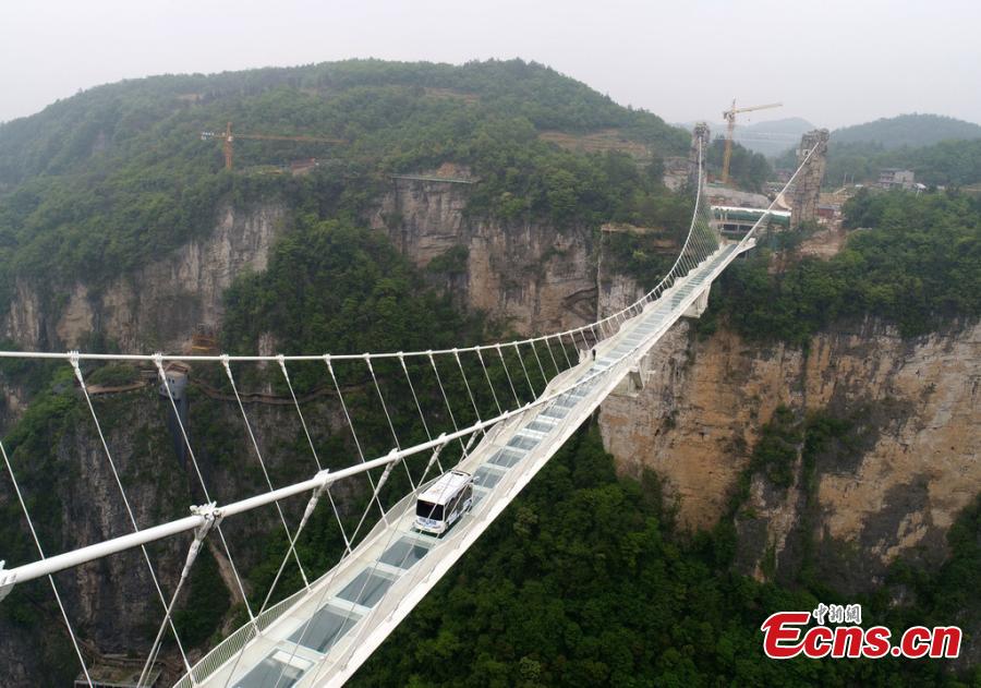 An automated bus drives on the glass bridge of the Grand Canyon scenic area in Zhangjiajie, Hunan Province, on April 24, 2019. The scenic area will offer the self-driving bus service, which can carry 25 people and reach a speed of up to 40 kilometers per hour.  (Photo/IC)