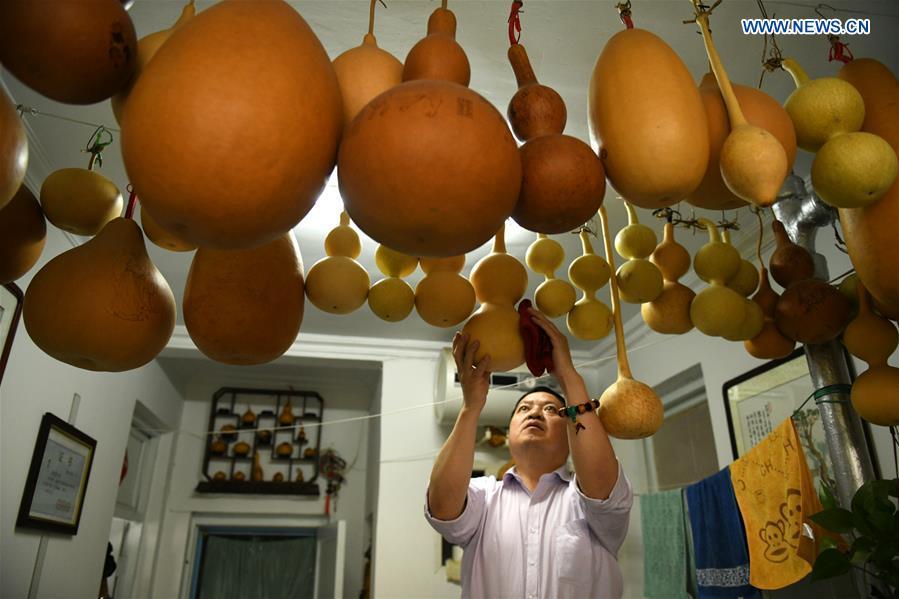 Craftsman Liu Chunpu wipes cucurbit pyrography works at a studio in Yuhua District of Shijiazhuang, north China\'s Hebei Province, April 23, 2019. Liu Chunpu, a staff member of Hebei Normal University, has devoted himself in cucurbit pyrography for more than 40 years. (Xinhua/Xu Jianyuan)