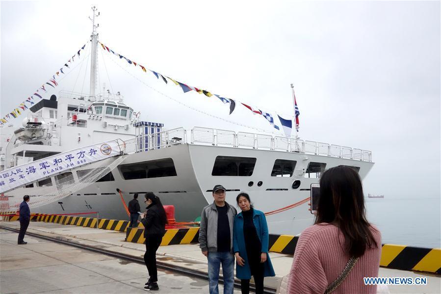 Visitors pose for a photo in front of hospital ship Peace Ark of the Chinese People\'s Liberation Army (PLA) Navy during a warship open day event in Qingdao, east China\'s Shandong Province, April 24, 2019. A warship open day event was held on Wednesday in Qingdao, as part the multinational naval events marking the 70th founding anniversary of PLA Navy. (Xinhua/Ma Jing)