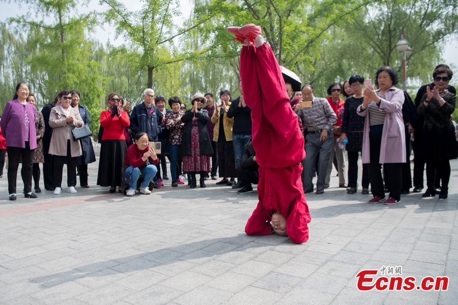Xiao xuerong, 68, draws a crowd as she practices handstands  in Xuefu Park in Taiyuan, Shanxi Province, April 26, 2019. (Photo/China News Service)