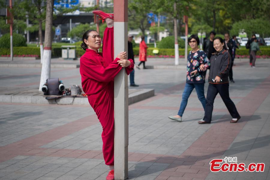 Xiao xuerong, 68, draws a crowd as she practices splits  in Xuefu Park in Taiyuan, Shanxi Province, April 26, 2019. (Photo/China News Service)