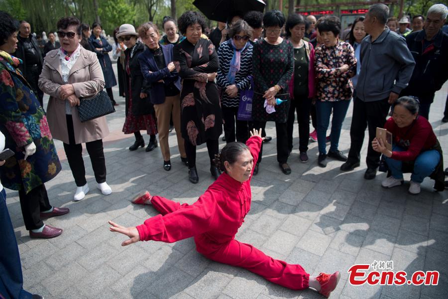 Xiao xuerong, 68, draws a crowd as she practices splits  in Xuefu Park in Taiyuan, Shanxi Province, April 26, 2019. (Photo/China News Service)