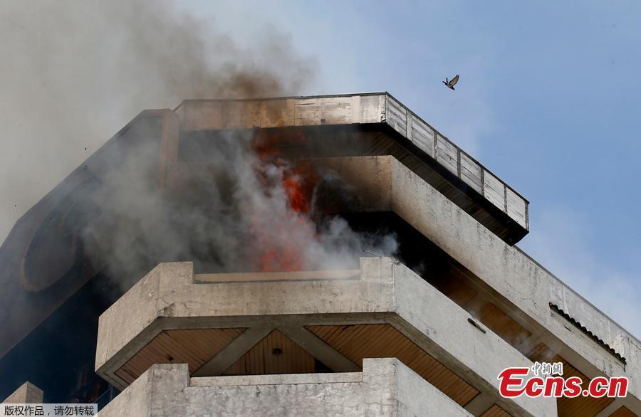 Fire burns in the top floors of a 21-story Pacific Coastal Plaza condominium in Manila, Philippines, April 29, 2019.  Officials say more than 100 firetrucks converged Monday to battle the blaze that hit the Pacific Coast Plaza condominium in the Paranaque city area of Manila, where one lane of a coastal road along Manila Bay was closed due to falling debris.  A woman died in the accident. (Photo/Agencies)