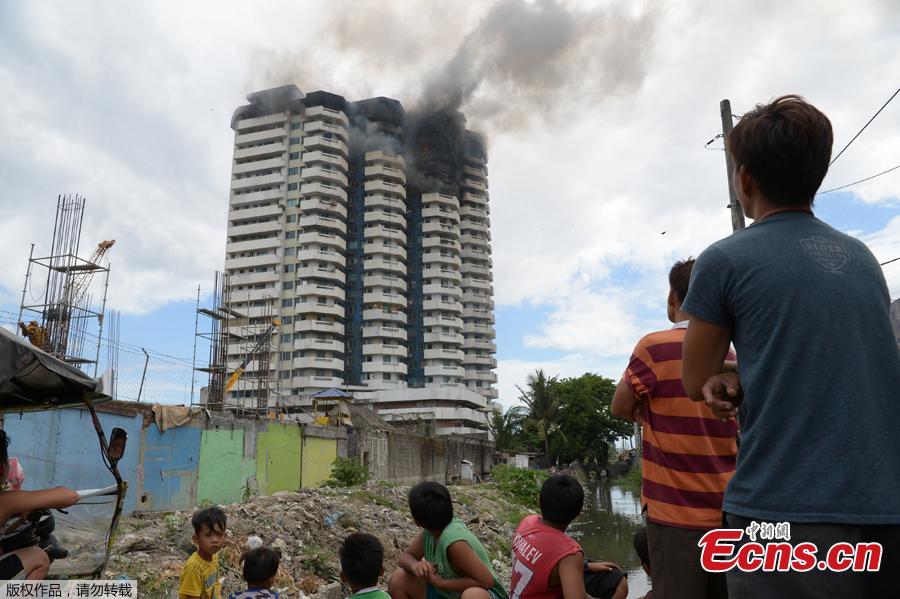 Residents watch as black smoke billows from a 23-storey residential building after a fire broke out in Paranaque City in suburban Manila, Philippines, April 29, 2019. A woman died in the accident. (Photo/Agencies)