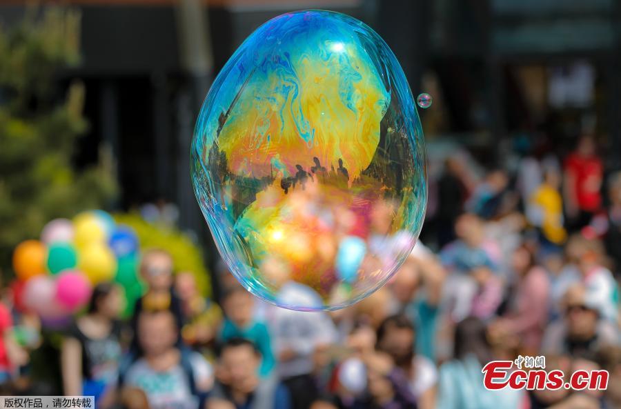 Participants in the Global Bubble Parade are reflected in a soap balloon in Bucharest, Romania, Sunday, May 5, 2019. Dozens took part in the Global Bubble Parade, an international event, held in 125 cities across 60 countries, according to the organizers, that brings together soap bubble fans.