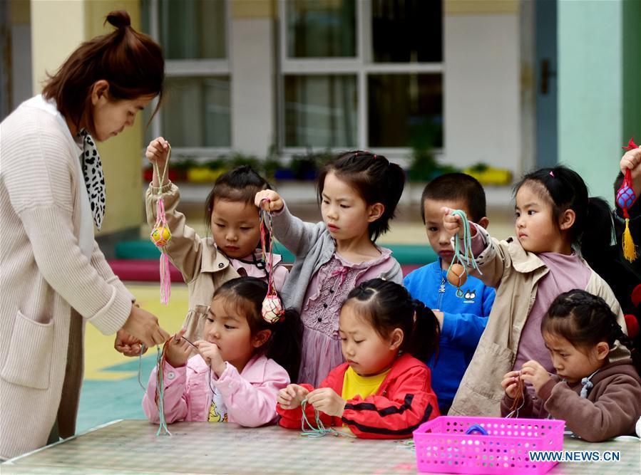 Children learn to knit a net for painted eggs under the guide of a teacher marking the upcoming \
