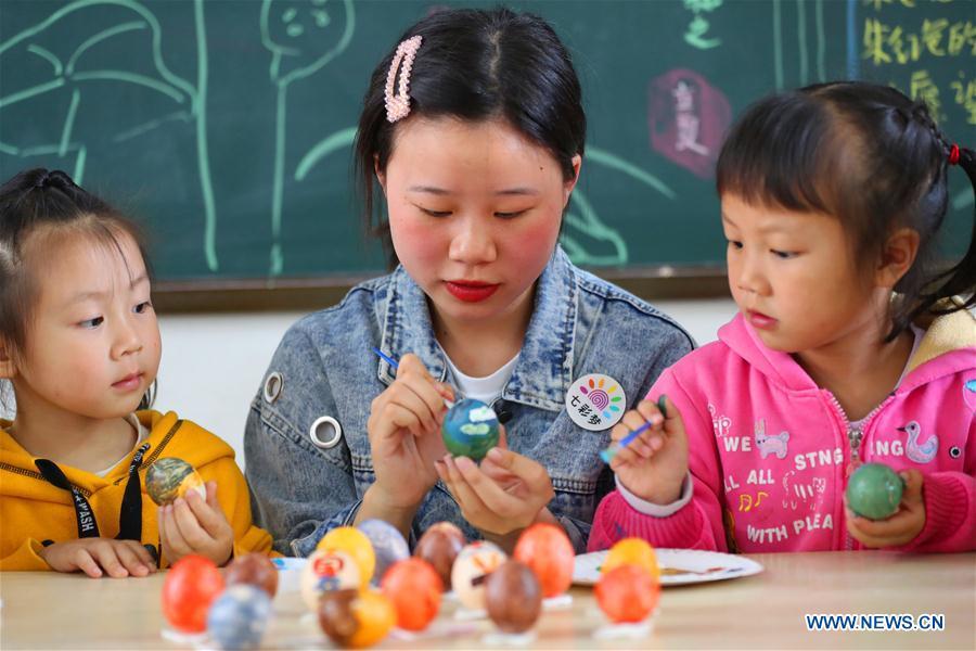 Children paint on eggs under the guide of a teacher to mark the upcoming \