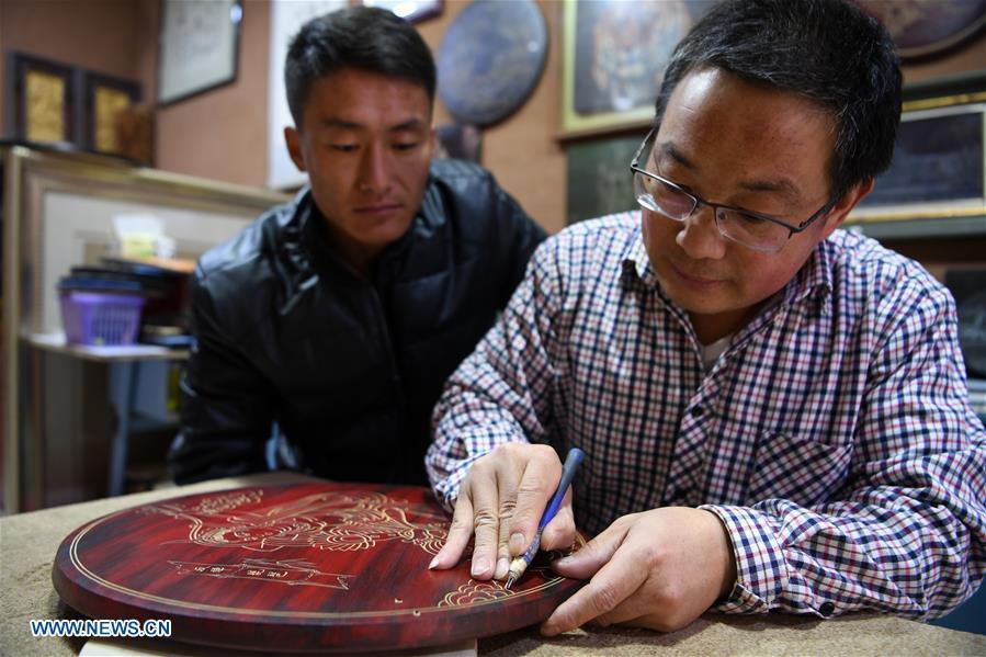 Shen Hongjie (R) teaches his apprentice at his workshop in Dunhuang, northwest China\'s Gansu Province, May 6, 2019. In 2004, Shen Hongjie was impressed by Dunhuang culture as he came here for sightseeing. He then left his hometown in central China\'s Hunan Province for Dunhuang. For 15 years, Shen Hongjie has been dedicated to promoting Dunhuang culture through woodcut. (Xinhua/Fan Peishen)