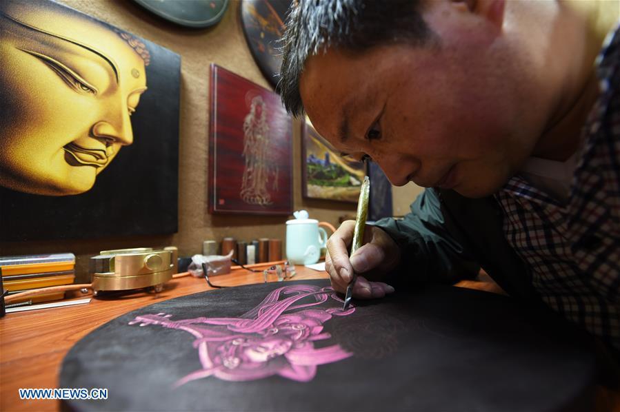 Shen Hongjie makes a woodcut at his workshop in Dunhuang, northwest China\'s Gansu Province, May 6, 2019. In 2004, Shen Hongjie was impressed by Dunhuang culture as he came here for sightseeing. He then left his hometown in central China\'s Hunan Province for Dunhuang. For 15 years, Shen Hongjie has been dedicated to promoting Dunhuang culture through woodcut. (Xinhua/Fan Peishen)