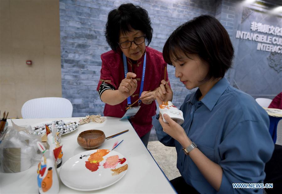 A reporter paints a clay sculpture at the intangible cultural heritage interactive area of the media center of the Conference on Dialogue of Asian Civilizations in the China National Convention Center in Beijing, capital of China, May 14, 2019. The Conference on Dialogue of Asian Civilizations will open on Wednesday. (Xinhua/Wang Yuguo)