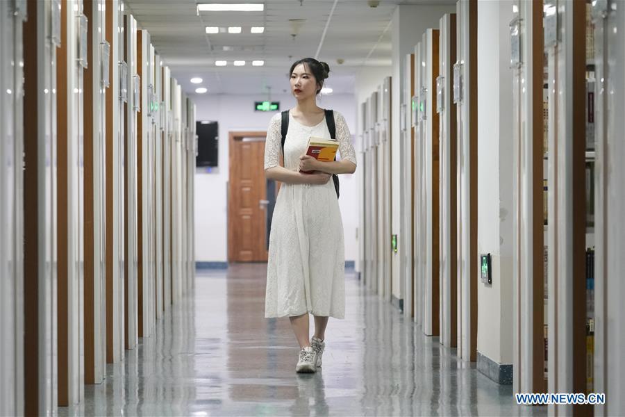 Feng Ganyu walks in a library at Beijing Normal University in Beijing, capital of China, May 12, 2019. A photographic exhibition themed \