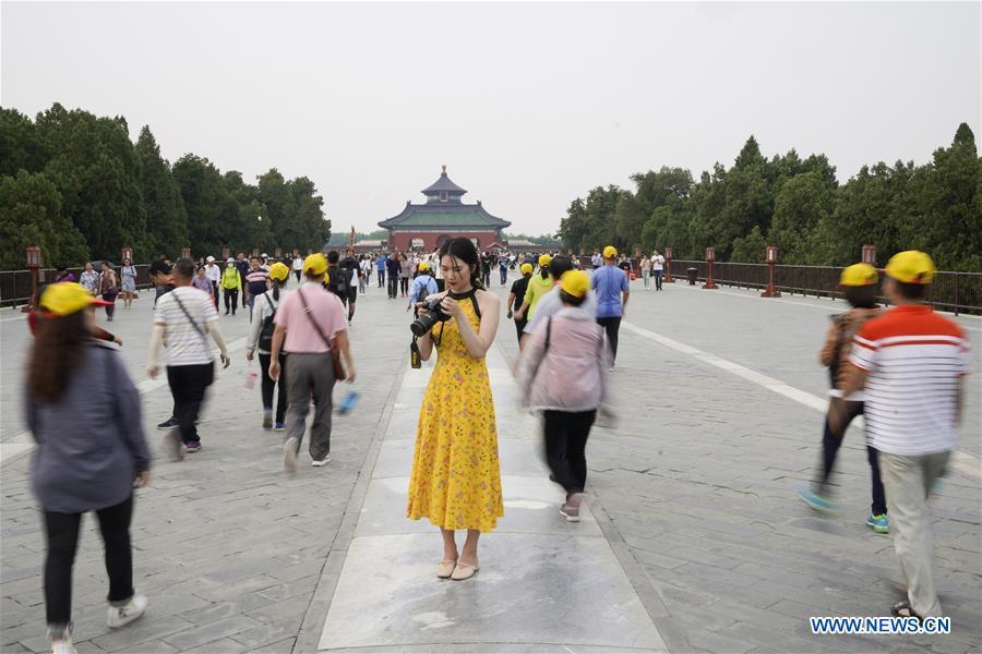Feng Ganyu checks the pictures she took at the Temple of Heaven in Beijing, capital of China, May 11, 2019. A photographic exhibition themed \