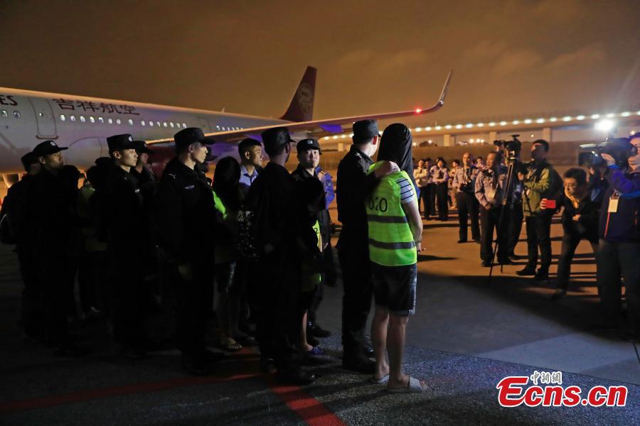 Police escort suspects caught in a social network and telecommunication fraud bust as they arrive at Pudong International Airport in Shanghai, May 14, 2019. Police detained the 57 suspects in Danzhou City of South China’s Hainan Province and then transported them to Shanghai as investigations continue.  (Photo: China News Service/Yin Liqin)