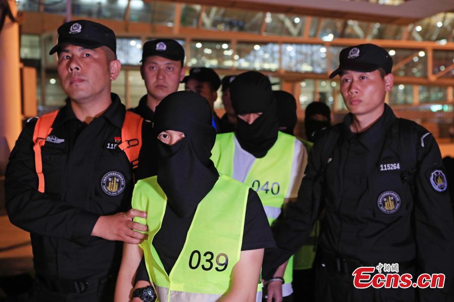 Police escort suspects caught in a social network and telecommunication fraud bust as they arrive at Pudong International Airport in Shanghai, May 14, 2019. Police detained the 57 suspects in Danzhou City of South China’s Hainan Province and then transported them to Shanghai as investigations continue.  (Photo: China News Service/Yin Liqin)