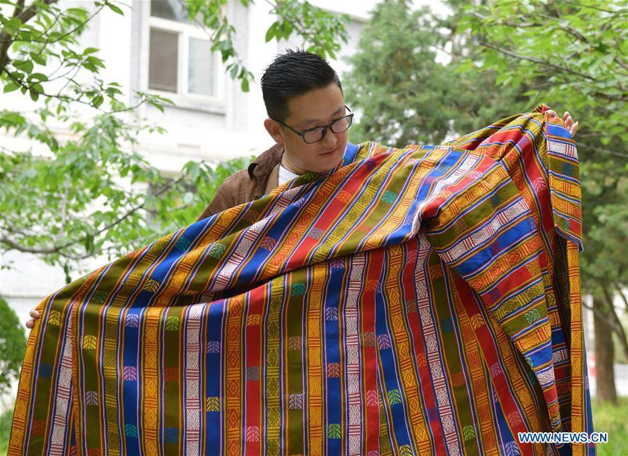 Sangay Tenzin displays traditional costumes made by his mother on the campus of the Beijing Language and Culture University in Beijing, capital of China, May 14, 2019. Sangay Tenzin, a Bhutanese student of Beijing Language and Culture University, is one of the photographers whose work was accepted by an exhibition themed \