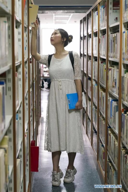 Feng Ganyu checks books in a library at Beijing Normal University in Beijing, capital of China, May 12, 2019. A photographic exhibition themed \