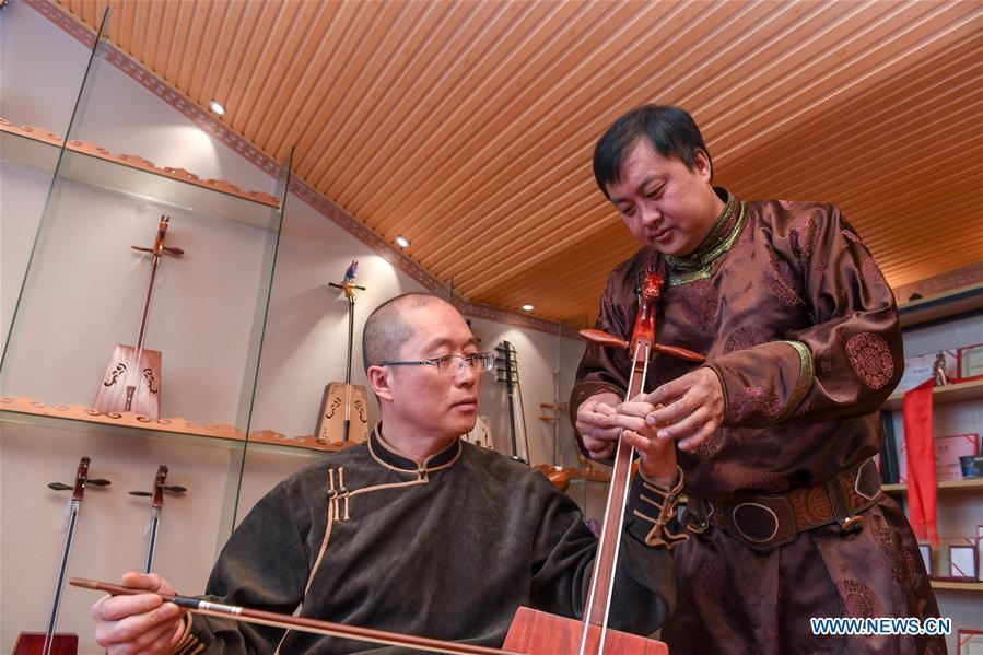 Baisu Gulang (R), a 37-year-old horse head fiddle maker, teaches his apprentice Yu Zhe to play horse head fiddle in Qian Golos Mongolian Autonomous County of Songyuan, northeast China\'s Jilin Province, May 15, 2019. Under his father\'s influence, Baisu Gulang has an ardent love in making and playing horse head fiddle, a traditional musical instrument favored by Mongolian ethnic group. He started learning to make horse head fiddle when he was 18 years old. In 2006, Baisu Gulang started a horse head fiddle making studio where he voluntarily teaches enthusiasts to make and play the instrument besides selling. (Xinhua/Zhang Nan)