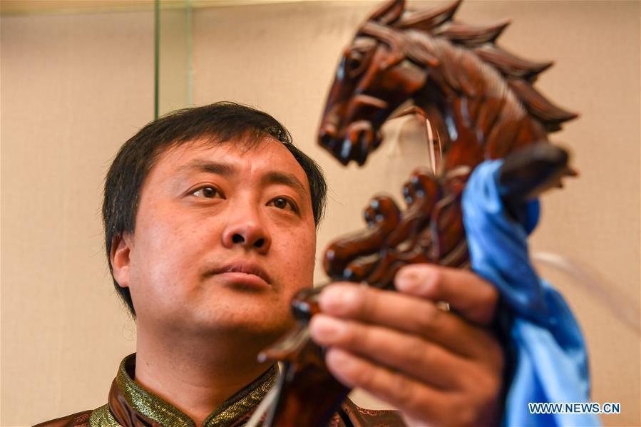 Baisu Gulang, a 37-year-old horse head fiddle maker, views a horse head fiddle in Qian Golos Mongolian Autonomous County of Songyuan, northeast China\'s Jilin Province, May 15, 2019. Under his father\'s influence, Baisu Gulang has an ardent love in making and playing horse head fiddle, a traditional musical instrument favored by Mongolian ethnic group. He started learning to make horse head fiddle when he was 18 years old. In 2006, Baisu Gulang started a horse head fiddle making studio where he voluntarily teaches enthusiasts to make and play the instrument besides selling. (Xinhua/Zhang Nan)