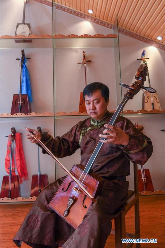 Baisu Gulang, a 37-year-old horse head fiddle maker, plays horse head fiddle in Qian Golos Mongolian Autonomous County of Songyuan, northeast China\'s Jilin Province, May 15, 2019. Under his father\'s influence, Baisu Gulang has an ardent love in making and playing horse head fiddle, a traditional musical instrument favored by Mongolian ethnic group. He started learning to make horse head fiddle when he was 18 years old. In 2006, Baisu Gulang started a horse head fiddle making studio where he voluntarily teaches enthusiasts to make and play the instrument besides selling. (Xinhua/Zhang Nan)