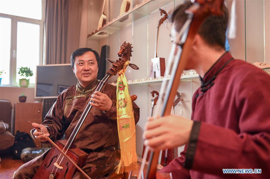 Baisu Gulang (L), a 37-year-old horse head fiddle maker, plays horse head fiddle in Qian Golos Mongolian Autonomous County of Songyuan, northeast China\'s Jilin Province, May 15, 2019. Under his father\'s influence, Baisu Gulang has an ardent love in making and playing horse head fiddle, a traditional musical instrument favored by Mongolian ethnic group. He started learning to make horse head fiddle when he was 18 years old. In 2006, Baisu Gulang started a horse head fiddle making studio where he voluntarily teaches enthusiasts to make and play the instrument besides selling. (Xinhua/Zhang Nan)