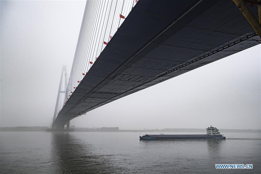 A boat passes under the Qingshan Yangtze River Bridge in Wuhan, central China\'s Hubei Province, May 16, 2019. The 7,548 meter-long Qingshan Yangtze River Bridge is now the widest bridge over Yangtze River. (Xinhua/Xiao Yijiu)