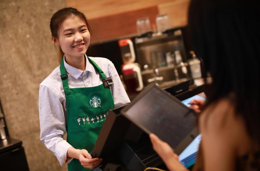An employee able to communicate in sign language works the counter at Starbucks China\'s first store with sign language capability in Guangzhou\'s Yuexiu district, May 19, 2019. (Photo provided to chinadaily.com.cn)

For hearing impaired customers at a Starbucks in Guangzhou\'s Yuexiu district, ordering coffee can be much easier. Starbucks China on Sunday opened its first store with sign language capability in the city\'s oldest downtown area to offer more possibilities to the deaf and hard of hearing community.

The store employs people with hearing challenges and provides equal training opportunities. All employees in the store are professional baristas and can communicate in sign language.

The store also is aimed at raising awareness and understanding of deaf and hearing impaired experiences in the workplace, according to Starbucks.

Starbucks employs over 100 people with special needs in China.

To nurture talent and create more opportunities for the deaf workforce, Starbucks has partnered with the Guangdong Deaf People Association to offer professional skills training and sign language courses.

\