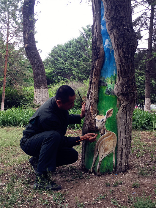 eng Shuxuan paints a deer on a tree trunk in the Zoological and Botanical Garden in Changchun, capital of Northeast China\'s Jilin Province, on Tuesday.  (Photo/chinadaily.com.cn)