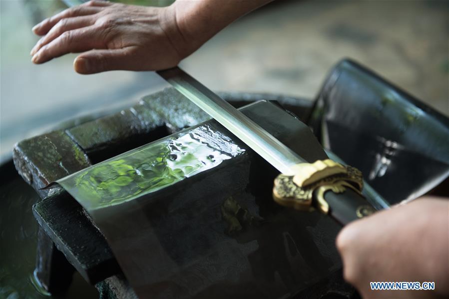 Wu Changyou, a co-worker of Zheng Guorong, burnishes a sword at Guyue Sword Studio in Longquan, east China\'s Zhejiang Province, May 21, 2019. For centuries, Longquan has been famed for its sword making industry. Zheng Guorong, 55, an intangible cultural heritage inheritor in Longquan Sword making, has been making sword for more than 30 years. Zheng regards sword as a symbol of spirit and devotes all to his career with awe. In his studio, the whole process of making a single sword takes two to three months, with steps including forming an idea, designing the sketch, preparing material and the final making and assembling. After setting up his studio, Zheng has trained more than 20 apprentices, who have all become sword smiths of great reputation. The old sword smith insists that Longquan sword, with a history of more than 2,500 years, deserves to be carried on in our time, both materially and spiritually. (Xinhua/Weng Xinyang)